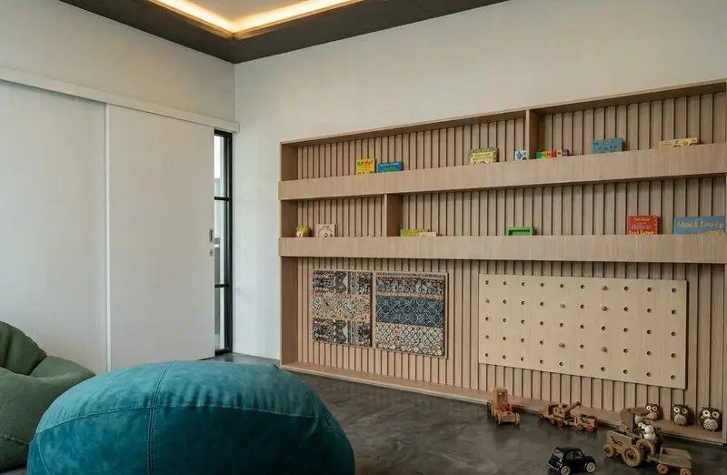 Sudut baca dengan rak buku rendah dan papan pasak